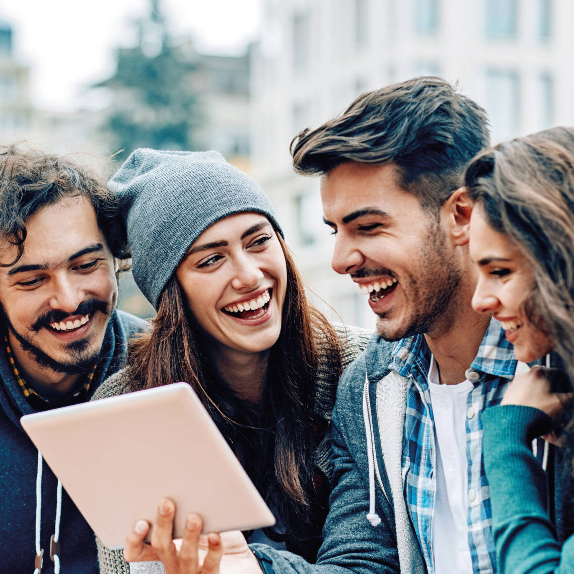 Gruppe junger Menschen schaut auf ein Tablet Computer.